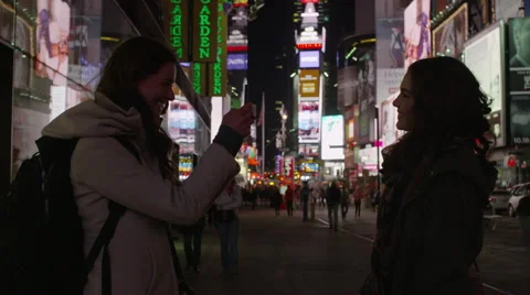 Medium shot of young women using camera phone in Times Square at night / New Stock Footage 42569184