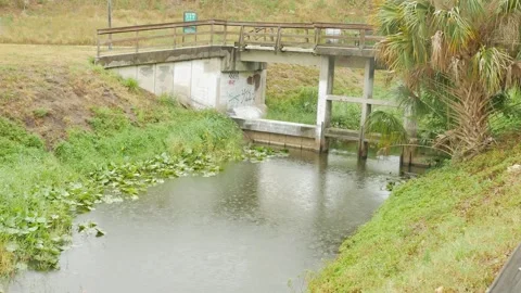 Medium Side view over an irrigation canal and green grass to a concrete and wood Stock Footage 276173885