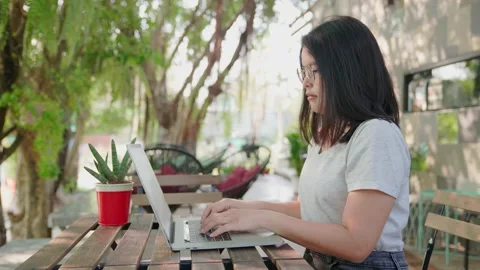 Medium side view shot of Young business woman sits in a cafe and works at a l Stock Footage 154696666