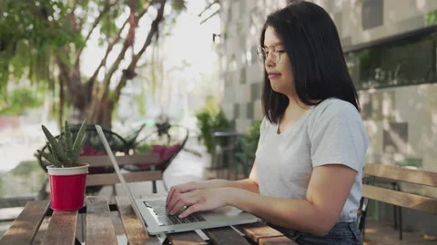 Medium side view shot of Young business woman sits in a cafe and works at a l Stock Footage 154697807