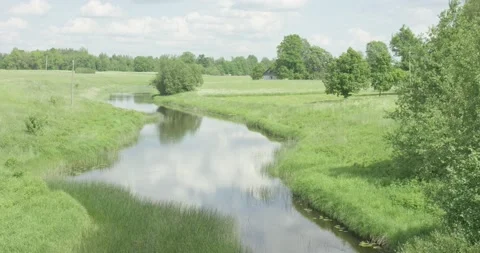 Medium size river flowing through green meadows in a sunny summer day Stock Footage 159980773