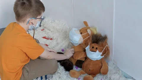 Medium-sized boy with blue eyes treats toys in masks from the virus Stock Footage 128055706