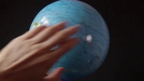 Medium-sized globe with human hands looking with a magnifying glass on a black Stock Footage 75002215