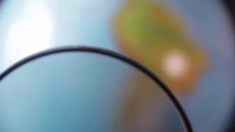 Medium-sized globe with human hands looking with a magnifying glass on a black Stock Footage 75002668
