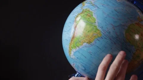 Medium-sized globe with human hands looking with a magnifying glass on a black Stock Footage 75172983
