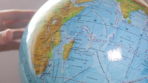 Medium-sized globe with human hands looking with a magnifying glass on a black Stock Footage 75187770