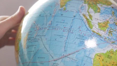 Medium-sized globe with human hands looking with a magnifying glass on a black Stock Footage 75187818