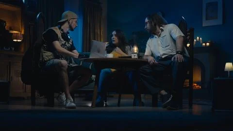 Medium-sized photo capturing two ghost hunters and a victim sitting at the table Stock-Fotos