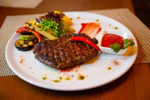 Medium-sized steak with vegetables in a cafe. Stock Photos