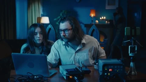 Medium-sized video of a ghost hunter and a victim sitting at the table in a dark Stock Footage 252382056