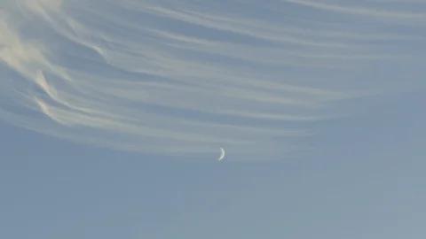 Medium speed timelapse of beautiful string of clouds moving and the moon 動画素材 104974328