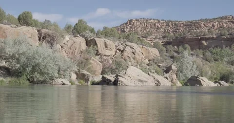 Medium static landscape shot of the San Juan River with large boulders and bu Stock Footage 336637353