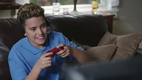 Medium tracking shot of African American teen gaming in his living room. Stock Footage 72322342