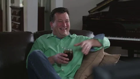 Medium tracking shot of man watching TV and laughing Stock Footage 71343215