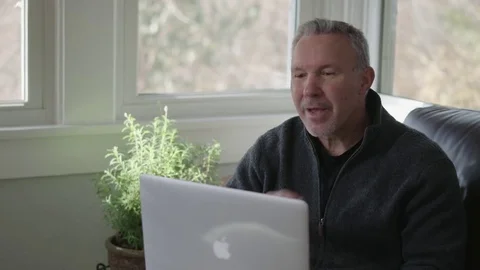 Medium tracking shot of older man working on a laptop Stock Footage 70810421