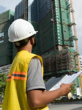 Medium vertical view Asian engineer looking up at nearby construction project Stock Photos