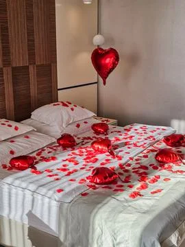 Medium View of Bed Decorated with Rose Petals and Heart Balloons Foto stock