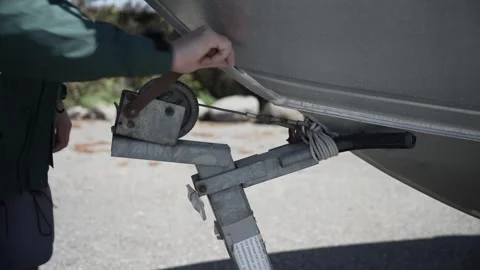 Medium view hand cranking down winch on boat trailer securing boat for Video stock 242167501