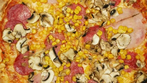 Medium view of rotating pizza. Lots of corn and salami on sliced pizza Stock Footage 195952990