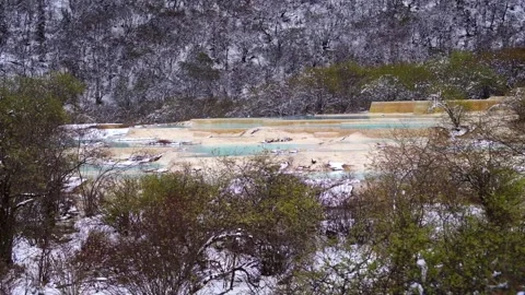 Medium View of Travertine Pools Through Snow-Dusted Trees in Huanglong Scenic 動画素材 339066763