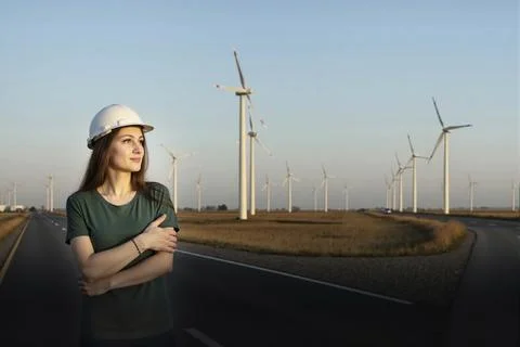 Medium-wide shot of a female engineer wearing a hard hat, standing beside a r Stock Photos