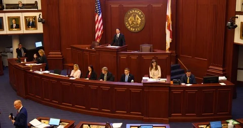 Medium wide shot Florida Senate Chamber's dais, seal, flags during debate Stock-Footage 107572389
