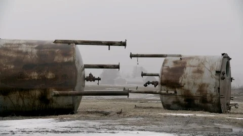 Medium Wide Shot of Two Large Water containers junked in farm field winter fog Stock Footage 89945125