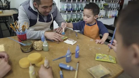 Medium wide shot of two little boys picking paints in a ceramic studio 動画素材 73298542