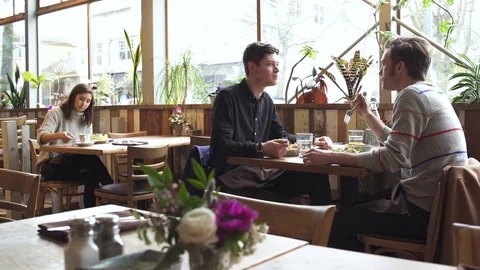 Medium wide shot of two men eating at a restaurant 動画素材 73299774