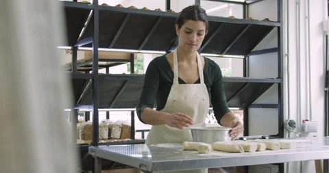 Medium wide view shot of young female small business owner making bread inside Stock Footage 277958897