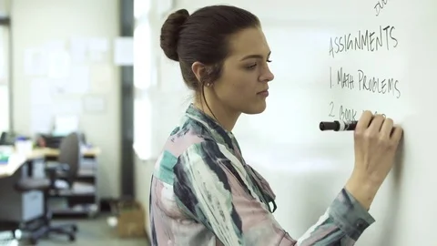 Mediums shot of teacher writing on board with marker Stock Footage 76567443