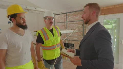In a meeting, construction workers discuss the project details with a Stock Footage 305820607