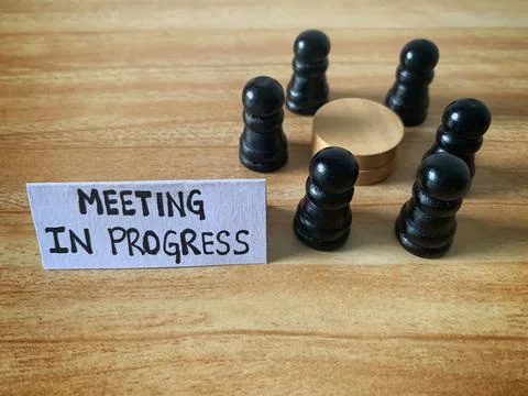 Meeting in progress text on a paper note with chess pawn circling a round table Stock Photos