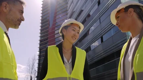 Meeting three multi-ethnic engineers talking about construction project outdoor Stock Footage 252084574