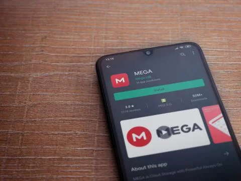 MEGA app play store page on the display of a black mobile smartphone on woode Stock Photos