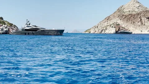 Mega yachts, one at anchor, one moving slowly Stock-Footage 258579268