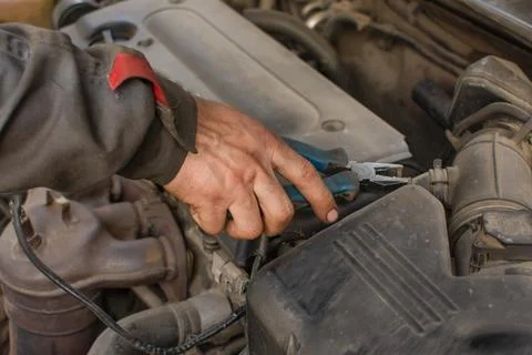 Mehanic repairs car engine, hand holds pliers Stock Photos