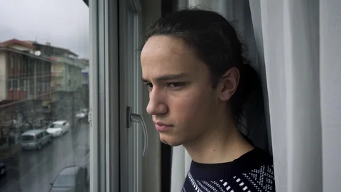 Melancholic millennial guy watching the empty streets from his window Stock Footage 127330397