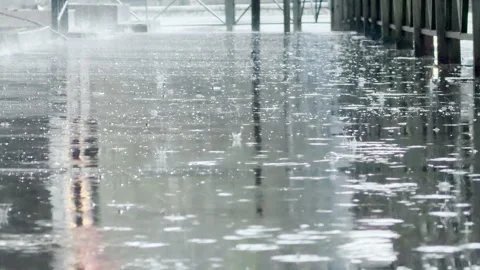 Melancholic Raindrops Splash into Deep Puddles Along a Somber City Sidewalk Stock Footage 334891970