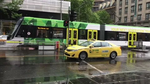 A Melbourne Tram and Yellow Taxi on a Wet Day Stock Footage