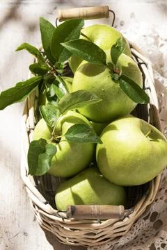 Mele Granny Smith in cestino. Frutta fresca verde su fondo bianco rustico Stock Photos
