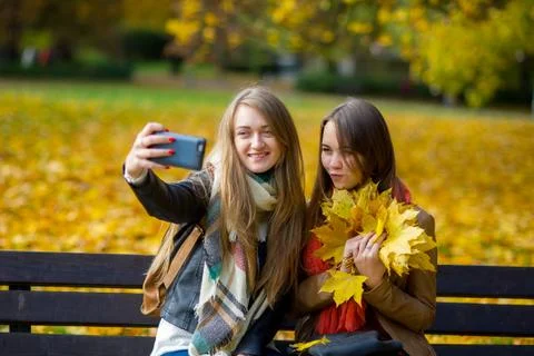 Mellow autumn. Two cute students makes a selfie in the park. Stock Photos