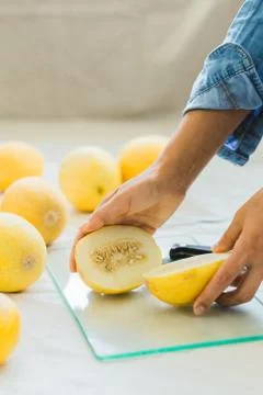 Melon berries on the kitchen table, hands cut melon into halves . Stock Photos