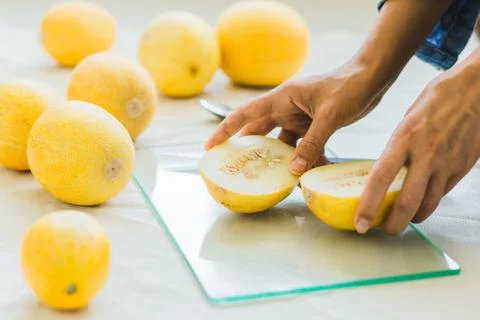 Melon berries on the kitchen table, hands cut melon into halves . Stock-Fotos