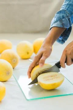 Melon berries on the kitchen table, hands cut melon into halves . Stock Photos