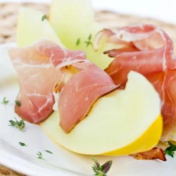 Melon with ham on a plate Stock Photos
