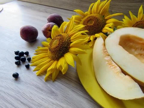 Melon in a plate on a table with sunflowers Stock Photos