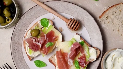 Melon with prosciutto toast with basil and honey. Antipasti snack. Stock Footage 235445675