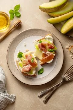 Melon with prosciutto toast with basil and honey. Antipasti snack. Stock Photos