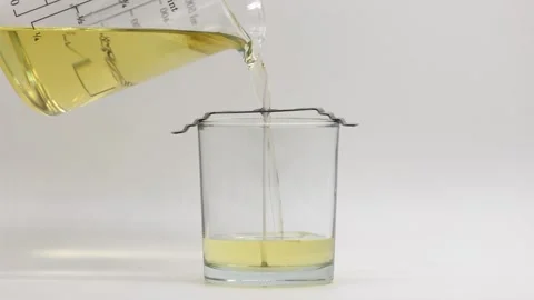 Melted candle wax being poured into glass jar with wick Stock Footage 344743074